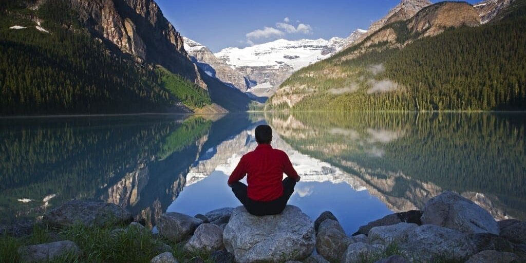 0814meditation01 Middle age male meditating on rock at Lake Louise, Alberta, Canada.