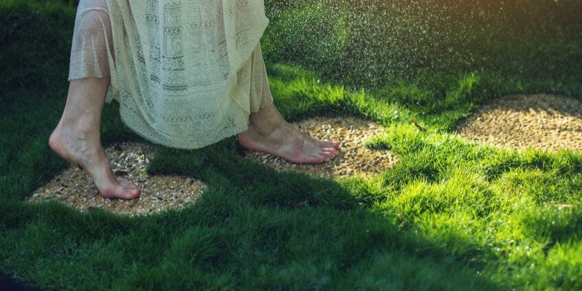 74306606 - girl walking barefoot on the stones in heart shape on green grass, concept of love for the nature