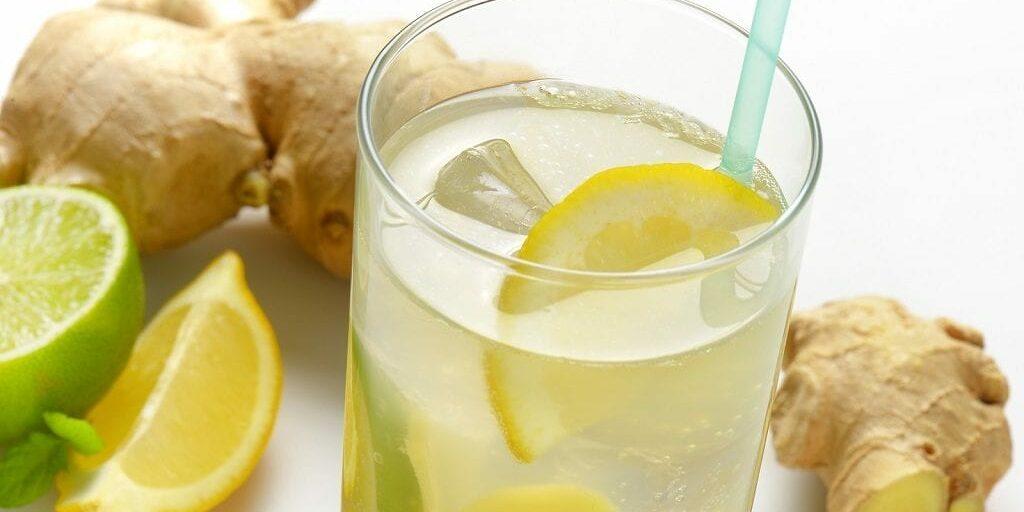 detail of glass of ginger ice tea with lemon and fresh ginger