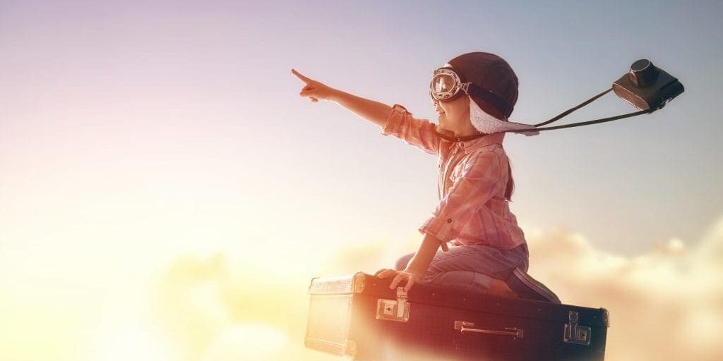 Dreams of travel Dreams of travel! Child flying on a suitcase against the backdrop of a sunset.