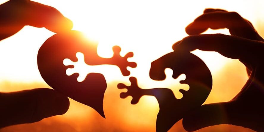 Two halves of the heart in the hands of people against the eveni Two halves of the heart in the hands of people against the evening sky, sunset. love, relationships.